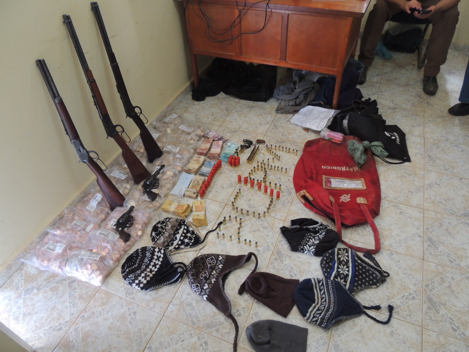 Parte do dinheiro roubado e armas encontrados com os dois bandidos presos.